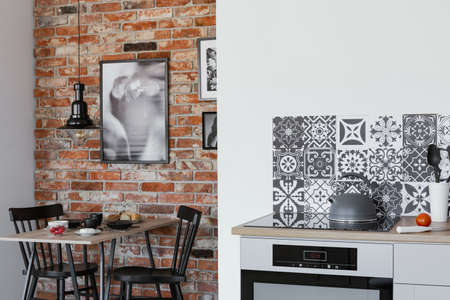 Kettle on electric stove in trendy kitchen with brick wall in dining roomの写真素材