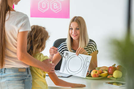 Helpful dietitian holding the chock, preparing healthy diet plan for her patientsの写真素材