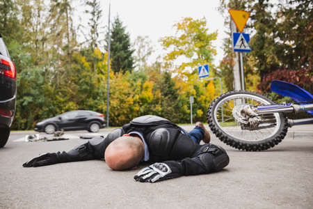Dead motorcycle driver laying on the street next to his motorcycleの写真素材