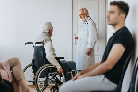 Senior man on a wheelchair enetring to doctor's officeの写真素材