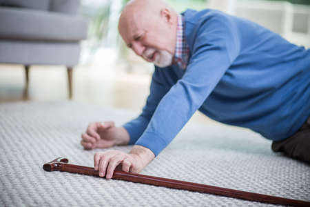 Senior man in blue sweater lying on the floor of his apartmentの写真素材
