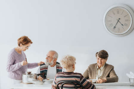 Group of senior people eating dinner together in nursing homeの写真素材