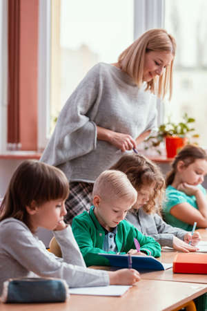 Young blonde haired teacher with children in the classroom