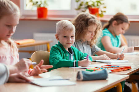 Happy children sit together at the table during the first physics lesson in the new school yearの写真素材