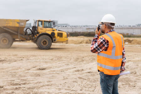 Man wearing reflective vest and a helmet calling by walkie-talkieの写真素材