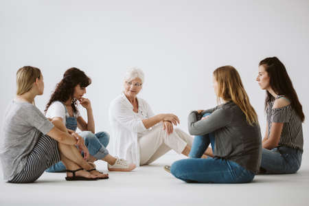 Women sitting on the floor during group psychotherapy with senior therapistの写真素材