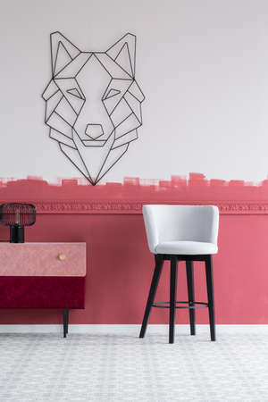 Pastel grey velvet chair next to stylish commode with pastel pink and burgundy drawersの写真素材