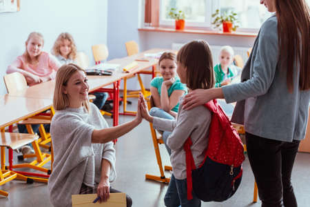 Girl with a red backpack says hello to her friends on her first day of schoolの写真素材