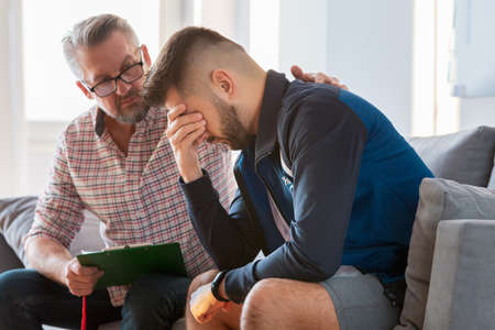 Young man with trauma talking with his psychotherapistの写真素材
