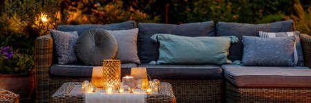 Warm summer night in the garden with trendy furniture, lights, lanterns and candles