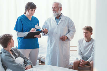 Intern and doctor writing something on legal pad during hospital visitの写真素材