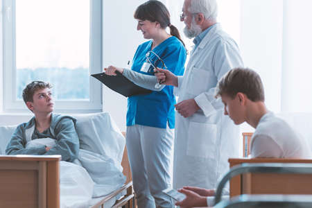 Senior male doctor with patient and female intern at the hospitalの写真素材