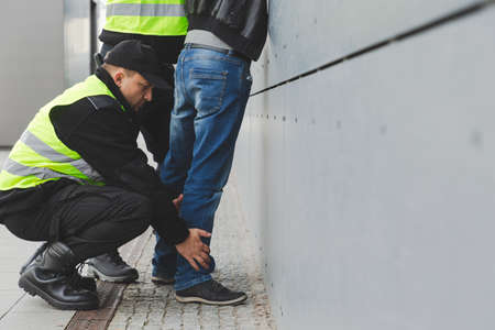 Two police officers detaining a drug dealer, copy space on the empty gray wall