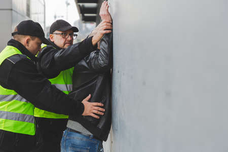 Two police officers detaining a criminal, copy space on the empty gray wallの写真素材
