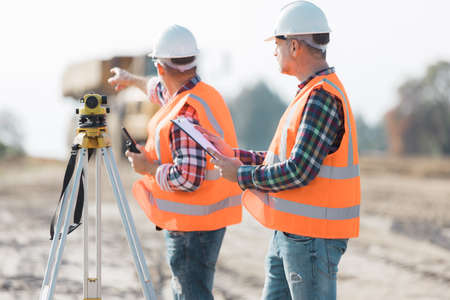 Two road construction workers using measuring device on the fieldの写真素材