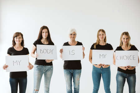 Group of women wearing jeans and lack t shirts and holding peaces of paper with sentence: My body is my choiceの写真素材