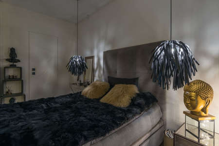 Elegant gray bed with black bedding in bright room interiorの写真素材