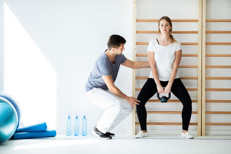 Professional physician helping his patient exercise with weightsの写真素材