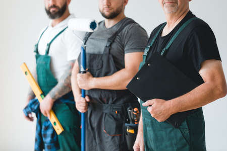 Crew of three professional builder wearing overalls standing in empty interiorの写真素材