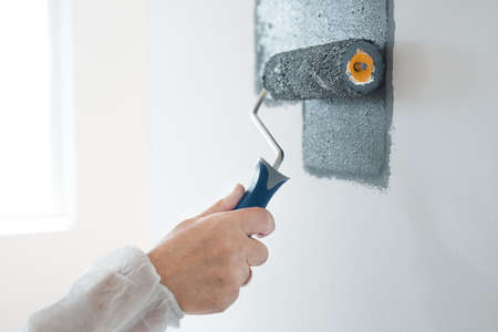 Closeup of renovation crew painting wall gray with painting rollの写真素材