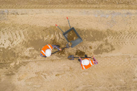 Two builders at work digging the soil with the shufflesの写真素材