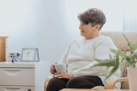Older woman drinking morning coffee in nursing home