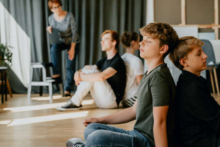 Group of teenagers on psychological workshops meditating in a roomの写真素材