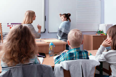 Happy children sit together at the table during the first physics lesson in the new school year