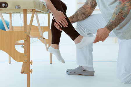 Physiotherapist touching the injured foot of a patientの写真素材