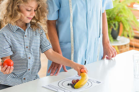 Little boy playing with fruit during a visit to a dietitianの写真素材