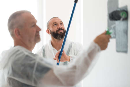 Closeup of renovation crew painting wall gray with painting rollの写真素材