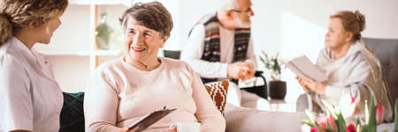 Happy aged woman talking to her caregiver in a nursing homeの写真素材