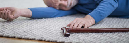 Senior man in blue sweater lying on the floor of his apartmentの写真素材