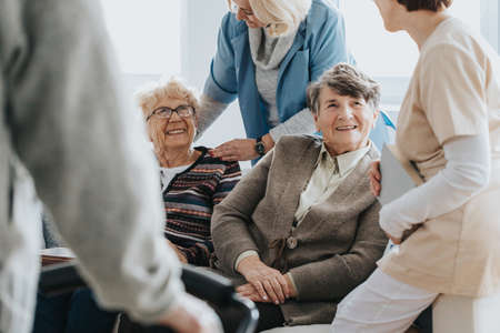 Senior people having fun together in nursing home with caregiversの写真素材