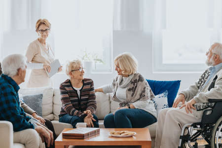 Group of older people talking together in a common room in nursing homeの写真素材