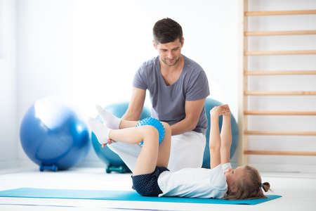 Professional physician explain to child how to perform an exerciseの写真素材
