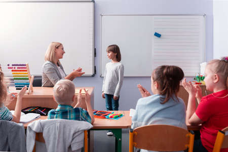 Young helpful teacher talks to a student standing at the blackboardの写真素材