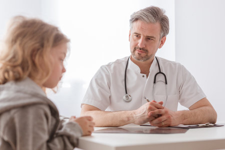 Helpful pediatrician and sick blond boy in a doctor's officeの写真素材