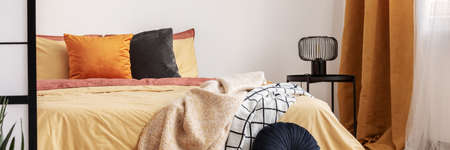 Stylish bedroom design with orange and yellow colors in modern apartmentの写真素材