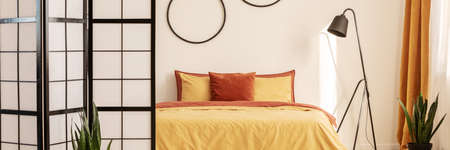 Stylish bedroom design with orange and yellow colors in modern apartmentの写真素材