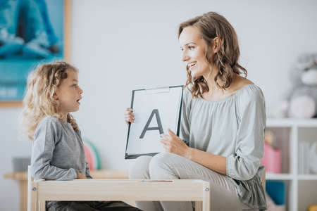 Young speech therapist and little patient practicing the pronunciationの写真素材