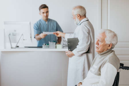 Older doctor taking patient's medical history before the appointmentの写真素材