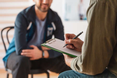Close-up of psychotherapist making notes about his patientの写真素材