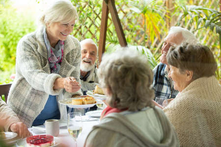 Cheerful group of elderly friends during barbeque at garden of family homeの写真素材