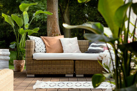 Pretty rattan furniture on wooden deck in the gardenの写真素材