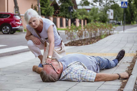 Helpful passerby checks the vital functions of the person who fainted on the streetの写真素材