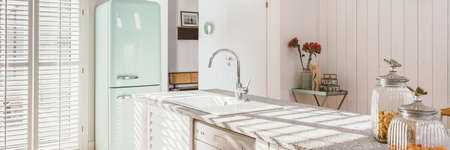 Bright kitchen interior with modern white furniture, pastel mint fridge and big floor to ceiling windowの写真素材