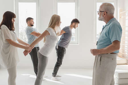 Young people stretching the muscles together on a group therapy
