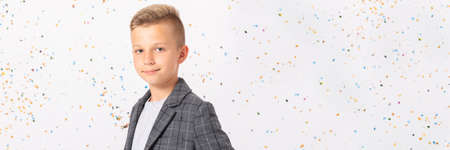 Elegant teenage kid wearing cool jacket standing in empty room, copy space on white wallの写真素材