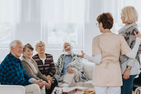 Head nurse is talking to new patients sitting on the sofa in a retirement homeの写真素材
